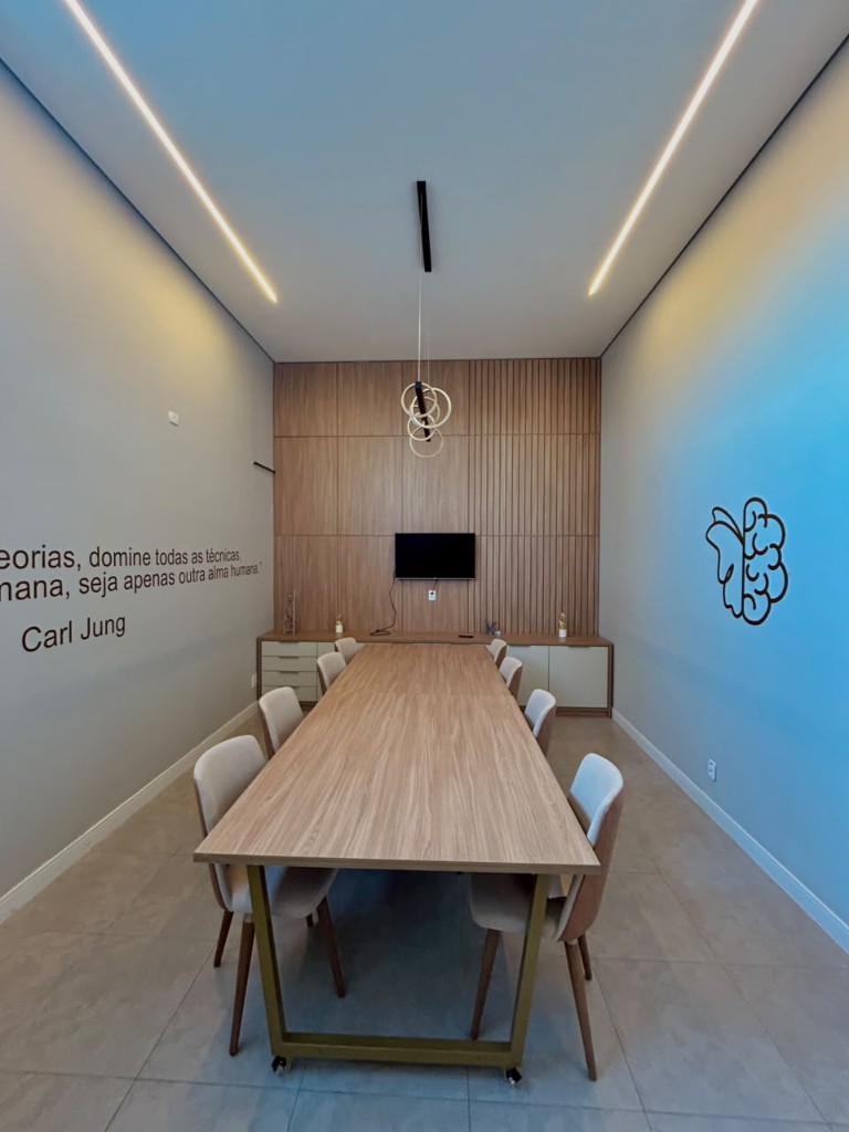 Sala de reunião com mesa, painel de madeira e a frase de Carl Jung